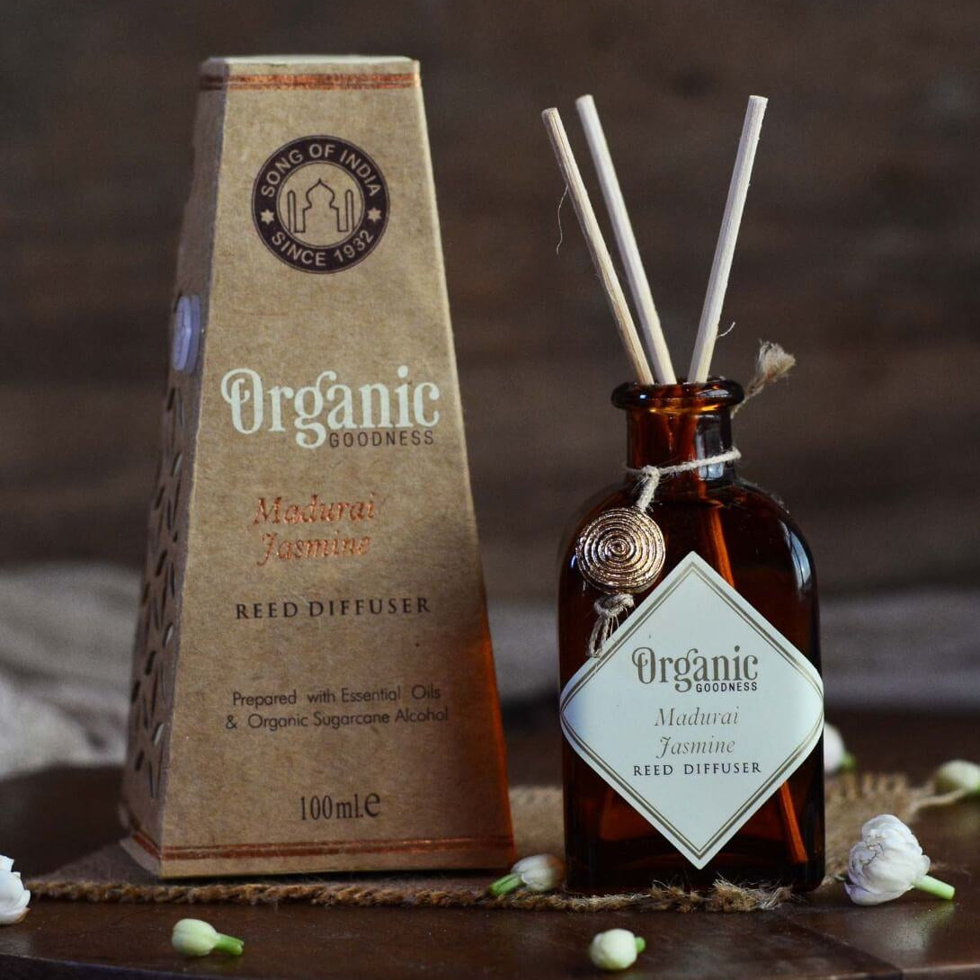 Reed diffuser set with brown packaging and amber bottle on a wooden surface.