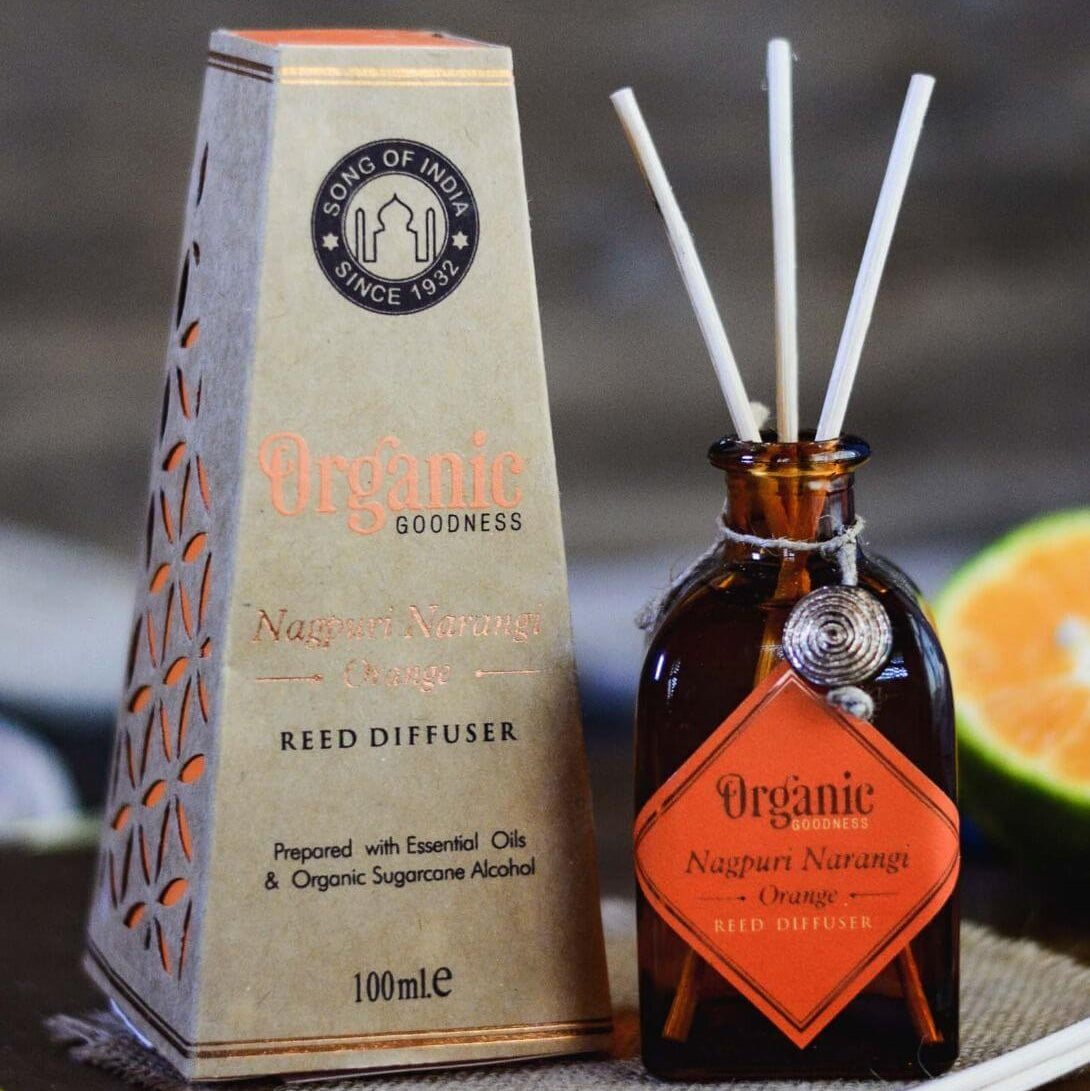 Reed diffuser packaging with bottle and orange slices on a blurred background